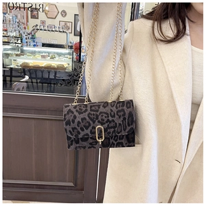 Sac bandoulière léopard gris avec chaîne dorée porté sur un manteau beige