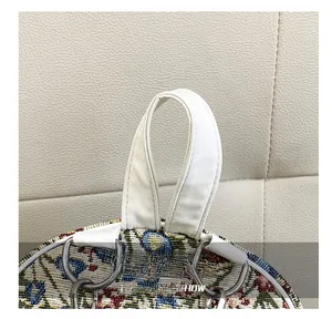 Detail showing the floral jacquard fabric and white leather handle with silver hardware