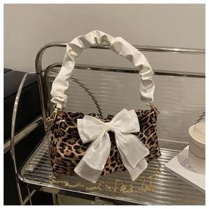 Detail view of leopard print handbag with white bow accent and ruffled handle