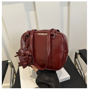 Detail of dark red retro PU leather handbag with heart charm and bow accents