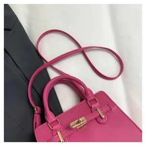 Detail of rose pink leather handbag with metallic lock and adjustable shoulder strap
