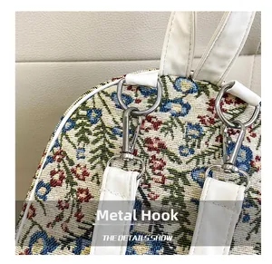 Detail of silver hardware hook and white leather strap on floral jacquard handbag