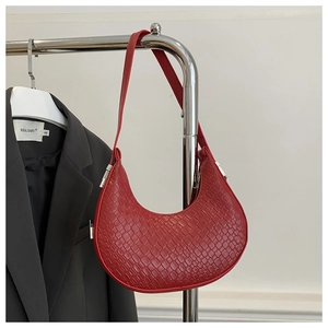 Détail du sac à bandoulière rouge en forme de croissant avec texture tressée et métal