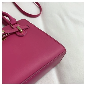 Close-up of fuchsia leather handbag featuring gold hardware and fine stitching detail