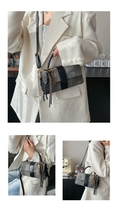 Detail of crossbody bag featuring grey-black patchwork, fringe tassel, and golden pendant