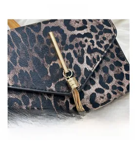 Detail der Handtasche mit Leopardenmuster, goldener Metallschiene, Kettengliedern und Quasten