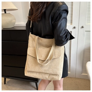 Detail view of the beige corduroy tote bag showing its texture and front pocket