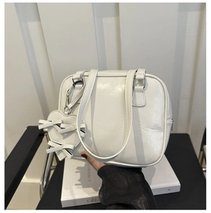Detail of white PU leather handbag featuring fine texture and bow heart charm