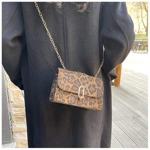 Détail du sac léopard à chaîne avec boucle dorée en U sur un manteau en laine noir