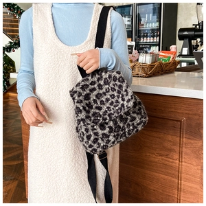 Gros plan du sac à dos en peluche léopard avec bretelles dans un décor de café chaleureux