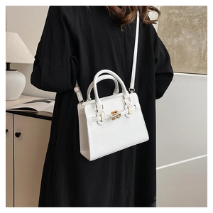 Detail of white leather handbag showing gold twist lock and smooth top handle texture