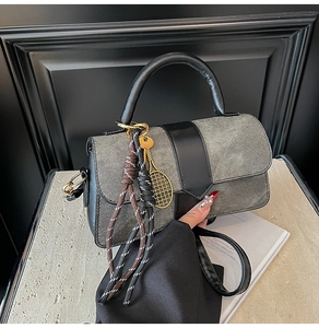 Detail of denim crossbody bag featuring a golden tennis racket charm and woven knot