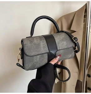Detail of grey denim and black leather patchwork bag with metallic gold buckle and strap
