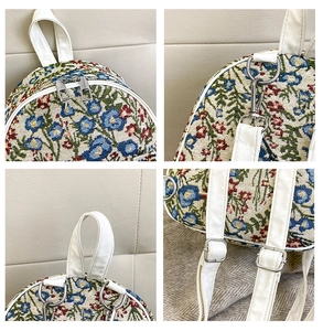 Detailed view of floral tapestry backpack with white leather handles and silver zippers