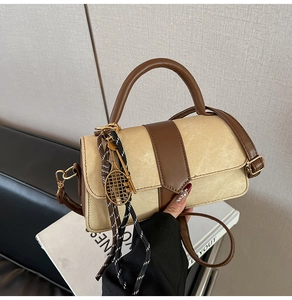 Close-up of beige canvas handbag with brown leather trim and tennis racket pendant detail