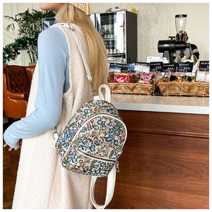 Floral mini backpack with embroidery pattern shown in a cozy cafe setting