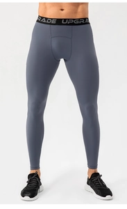 Detail of grey men's compression pants with elastic waistband featuring UPGRADE lettering