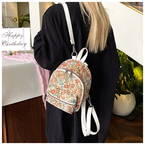 Rear view of model wearing a mini floral jacquard backpack with white PU leather straps