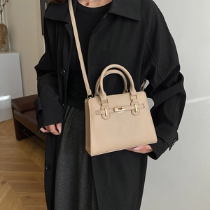 Elegant apricot leather handbag with belt detail and gold lock, crossbody view on model