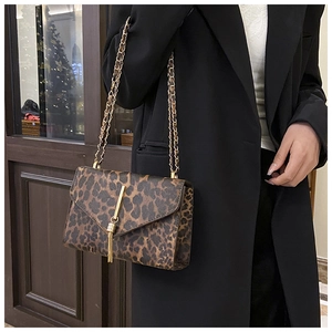 Detail der Leoparden-Tasche mit goldener Kette und Quasten-Anhänger an einem Model