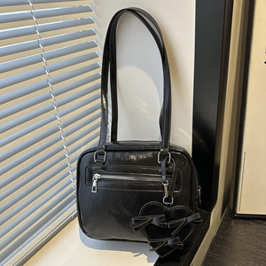 Minimalistische schwarze glänzende Handtasche mit Herzanhänger auf Fensterbank