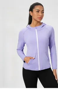 Détail d'une veste de yoga violette ajustée avec fermeture éclair blanche et poches
