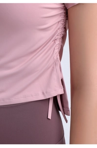 Detailed view of adjustable side drawstrings and split hem on pink yoga crop top