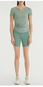 Detail view of sage green yoga top with side ruching and breathable athletic fabric