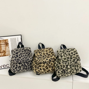 Trois sacs à dos en peluche à motif léopard en bleu, marron et vert sur un socle blanc