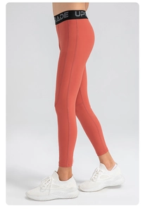 Gros plan sur le legging de sport rouge brique avec ceinture élastique et coutures plates