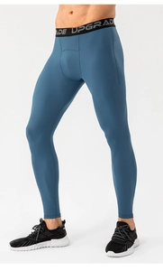 Detail of blue compression sports pants featuring a wide elastic waistband with UPGRADE text