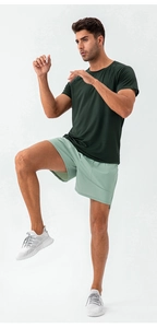 Close-up of quick-dry mesh fabric detail on men's dark green fitness t-shirt and light shorts