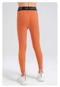 Detail showing high-waist orange athletic leggings with black Upgrade elastic waistband