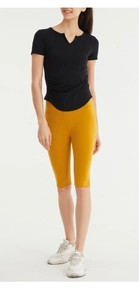 Detail of V-neck ruched workout top and yellow high-waisted yoga shorts on model