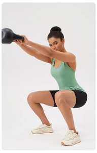 Donna in canotta sportiva verde menta che esegue squat con kettlebell