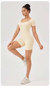 Vista laterale della tuta da yoga beige con scollo quadrato, maniche corte e sneakers