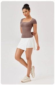 Dettaglio top aderente marrone con scollo a U e gonna da tennis bianca a strati