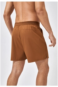 Dettaglio dei pantaloncini sportivi marrone caramello da uomo con elastico in vita e spacco