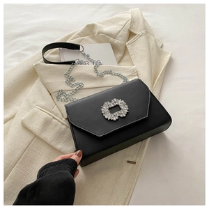 Close-up of black leather square bag with crystal buckle and metal chain strap