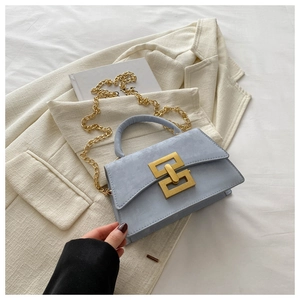 Close-up of a light blue crossbody bag featuring a golden interlocking buckle and chain