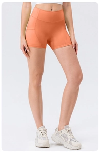 Detail of high-waist orange yoga shorts featuring a functional side pocket for a phone