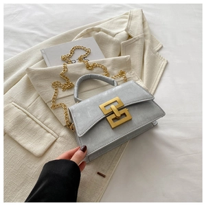 Detail of silver flap handbag with golden geometric metal lock and chain strap