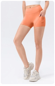 Detail of high waisted orange yoga shorts with side pockets for sports and fitness