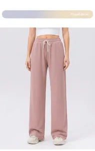 Dettaglio dei pantaloni sportivi a gamba larga rosa loto con trama a nido d'ape