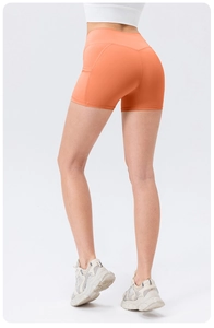 Rear view of high-waist bright orange yoga shorts showing peach lift and side pocket