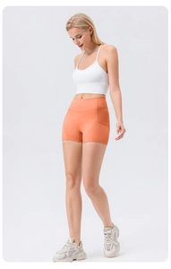 Close-up of bright orange high-waist yoga shorts with functional side pocket detail