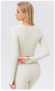 Detail of slim fit white yoga top with thumbholes and high waisted fitness leggings