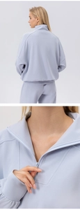 Detail view of half-zip collar and raglan sleeve on women's light blue sports sweatshirt