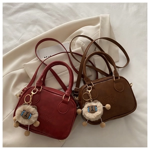 Detail of vintage tote bags in reddish-brown and dark coffee with bear pendants