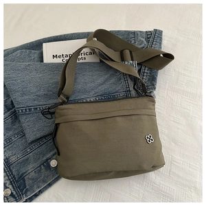 Olive nylon passport bag with adjustable strap and silver clover badge on fabric